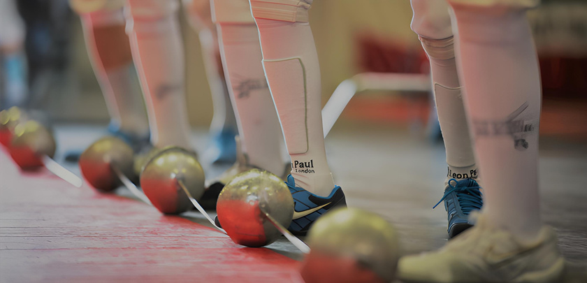 a row of fencers standing in a line with their feet on the ground with saber in front of their feet wearing west coast fencing academy fencing socks.