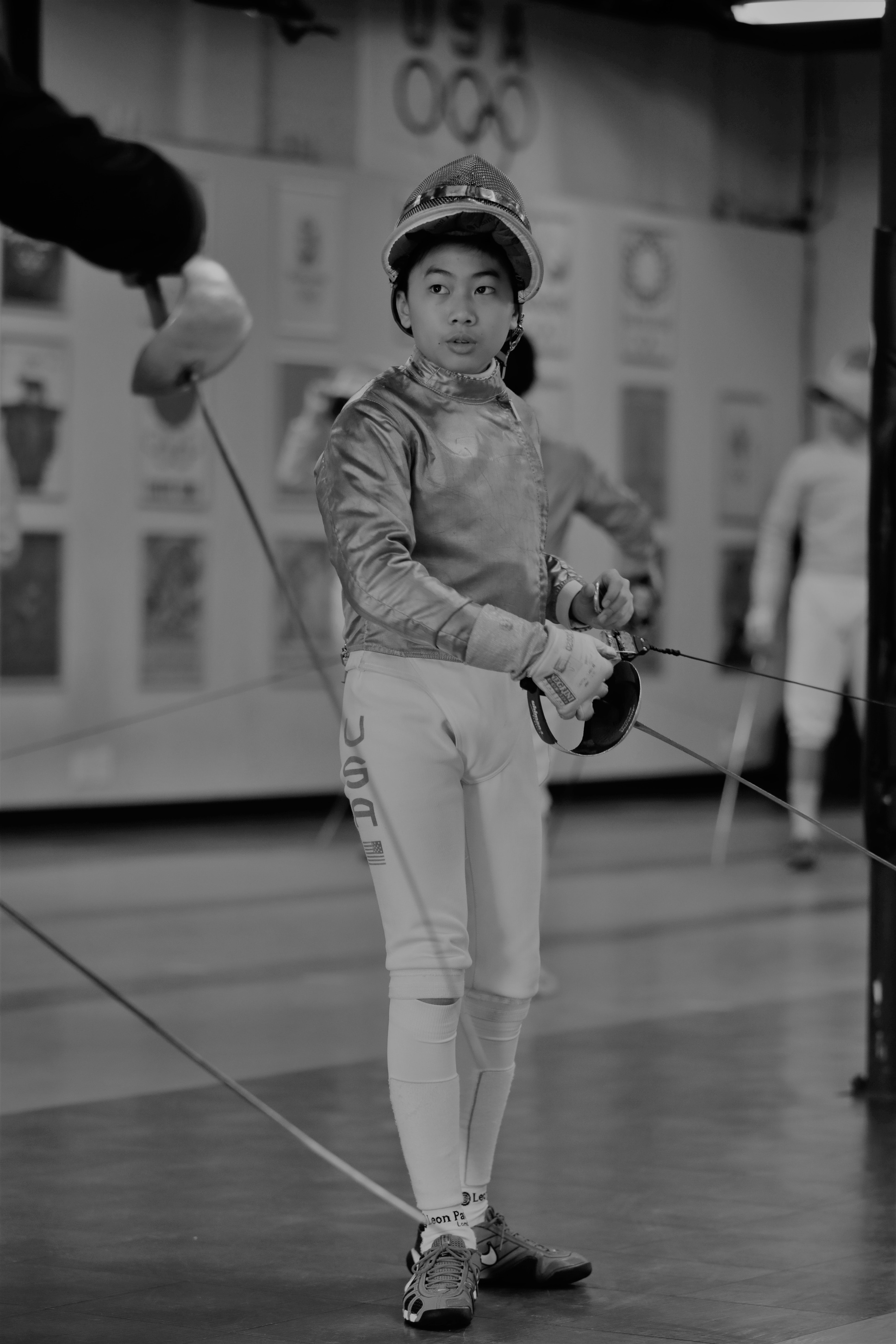 a black and white photo of a person in fencing gear taking fencing private lesson